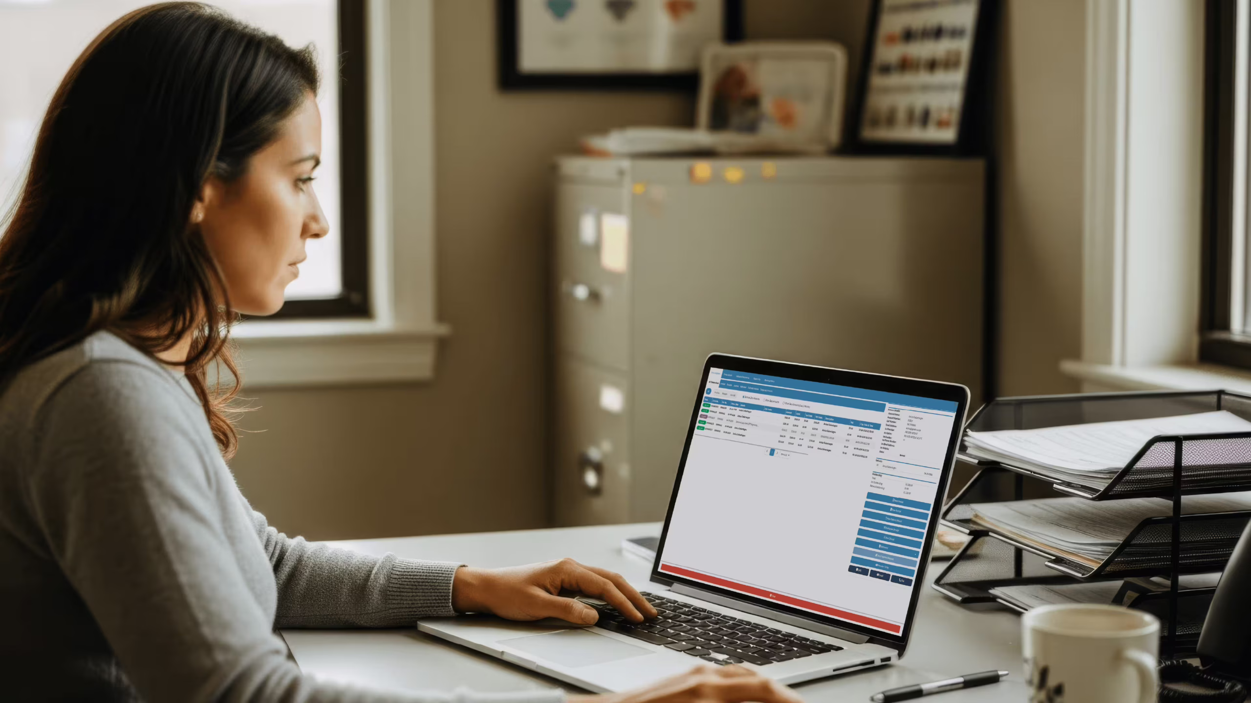 Medical biller reviewing a claim in basic medical billing software on a laptop in a small US practice office
